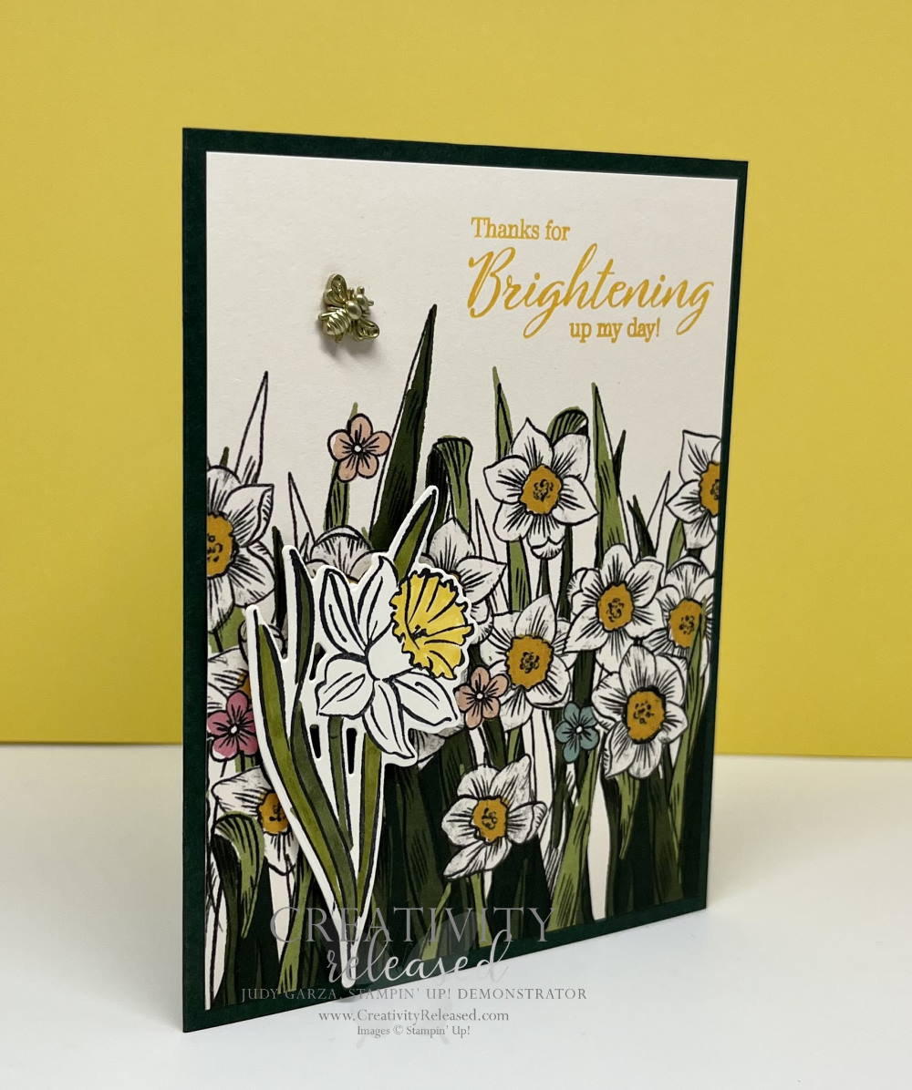 A side view of a greeting card with yellow and white Daffodils the sentiment "Thanks for Brightening up my day." It has a bumblebee trinket buzzing over the flowers. All products are by Stampin' Up!