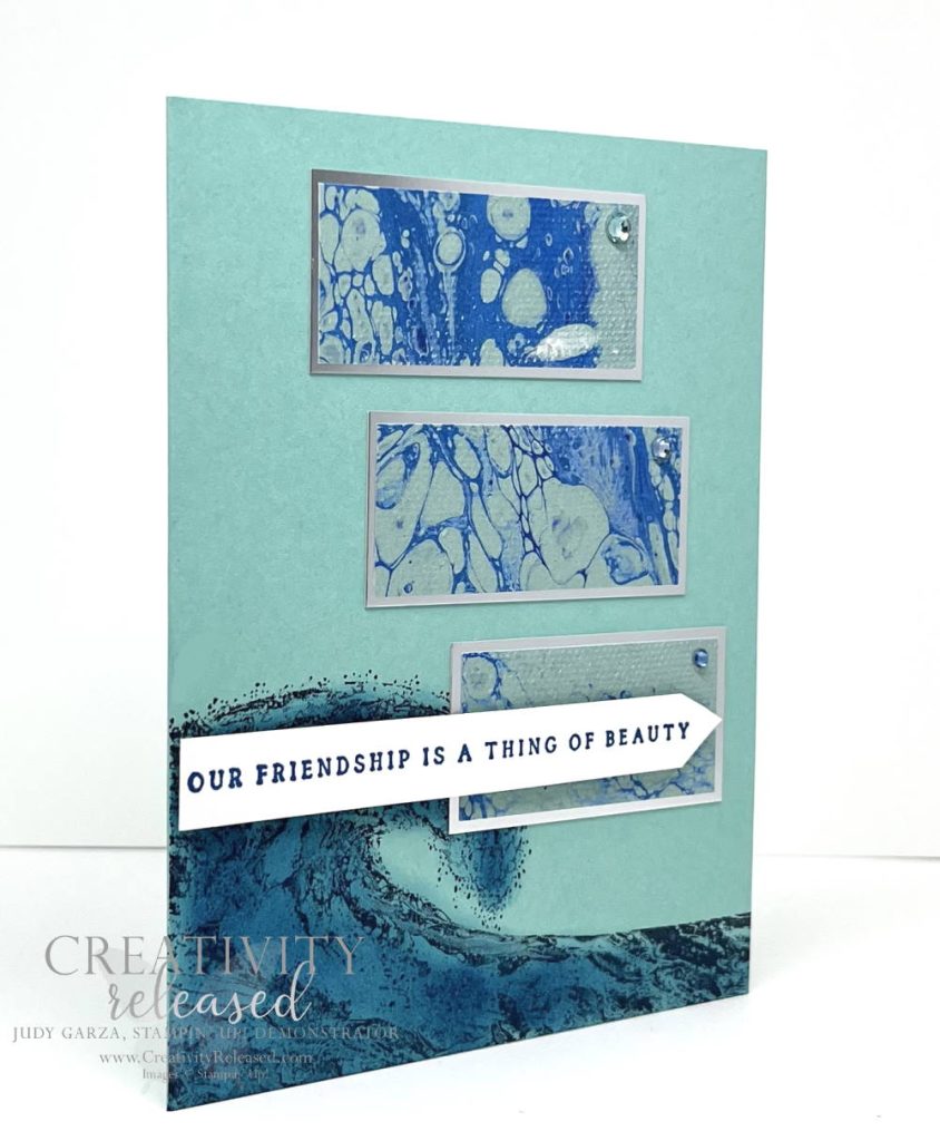 A side view of a friendship card done in oceanic colors with an image of a large wave along the bottom.